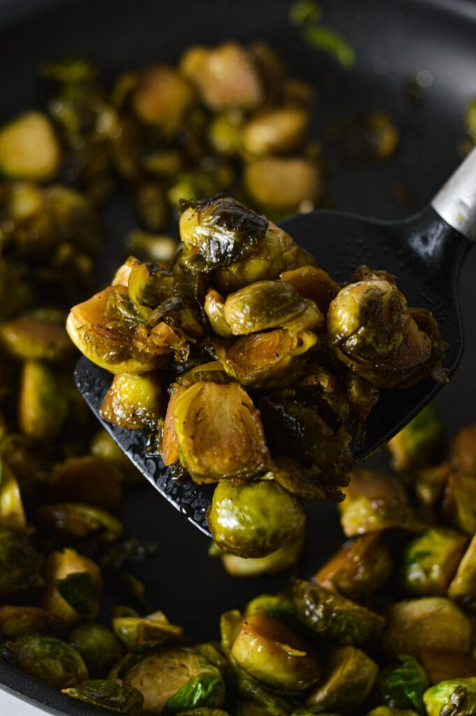 A kitchen spatula holding up some Stovetop Balsamic Honey Brussels Sprouts.