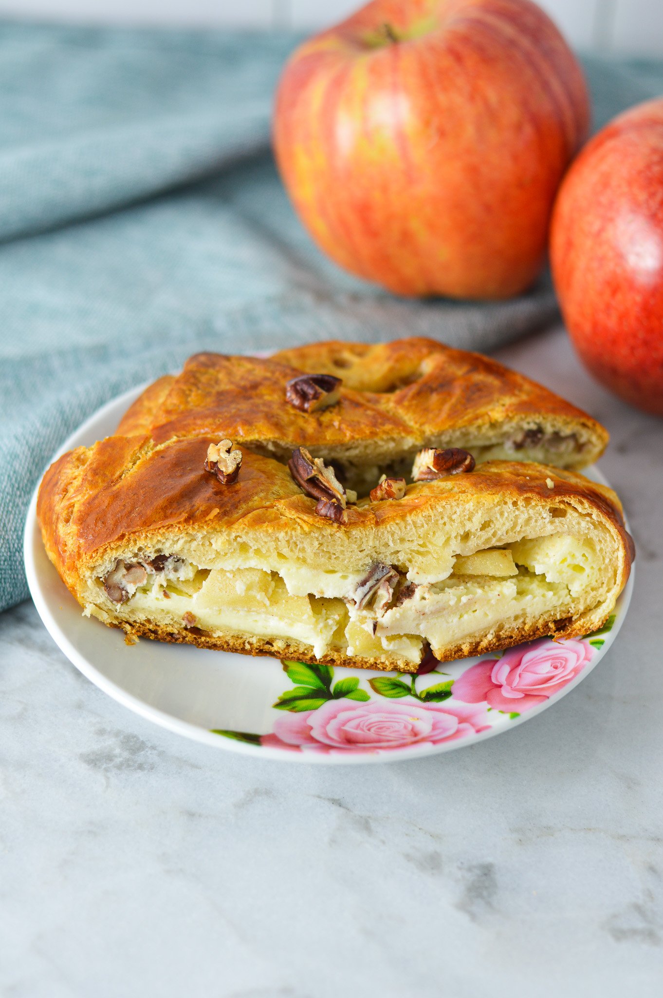 A small plate with a couple of slices of Easy Apple Pecan Cream Cheese Pastry Braid, with the apple and cream cheese filling clearly showing.