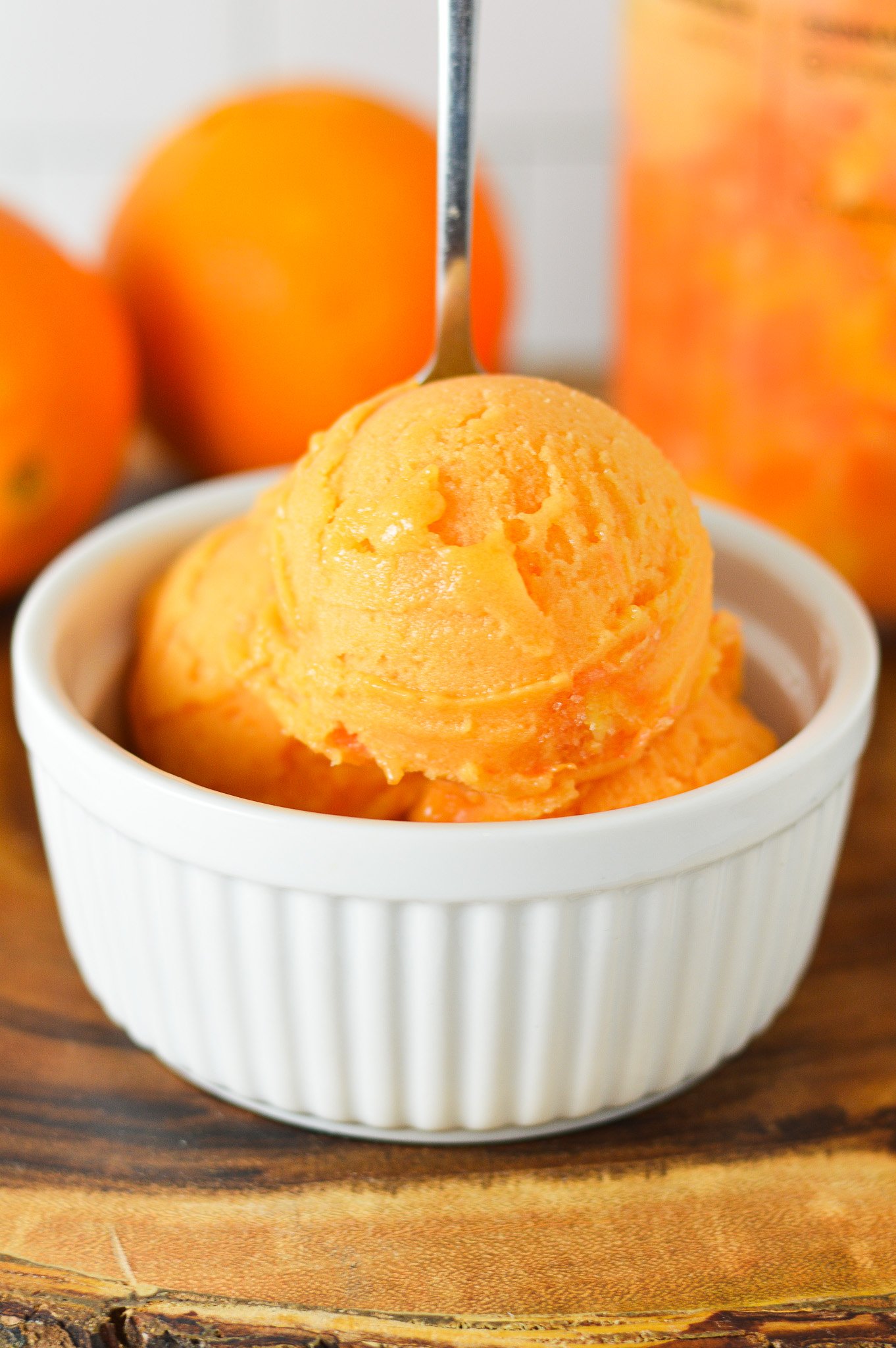 A small bowl full of Ninja Creami Cara Cara Orange Sorbet with a small spoon sticking out of the cold treat.