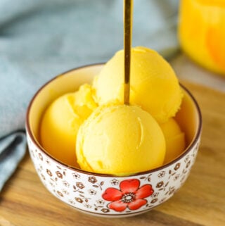 A small bowl full of Ninja Creami Peach Sorbet, with a small spoon inside the scoops of sorbet.