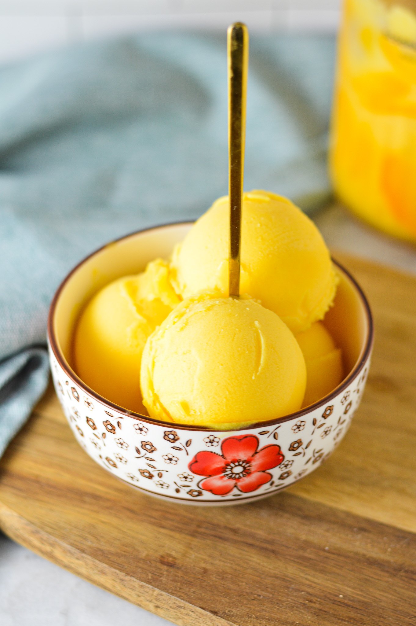 A small bowl full of Ninja Creami Peach Sorbet, with a small spoon inside the scoops of sorbet.
