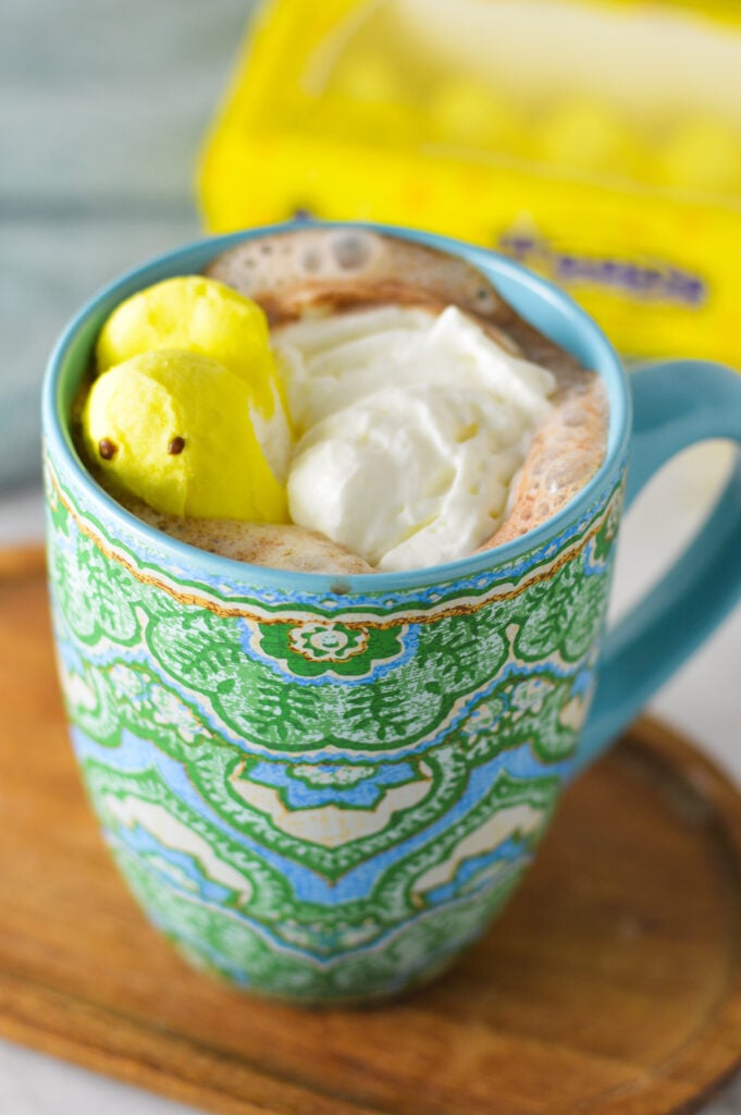 A large colorful mug filled with Peeps Hot Chocolate, with a package of marshmallow peeps in the background.