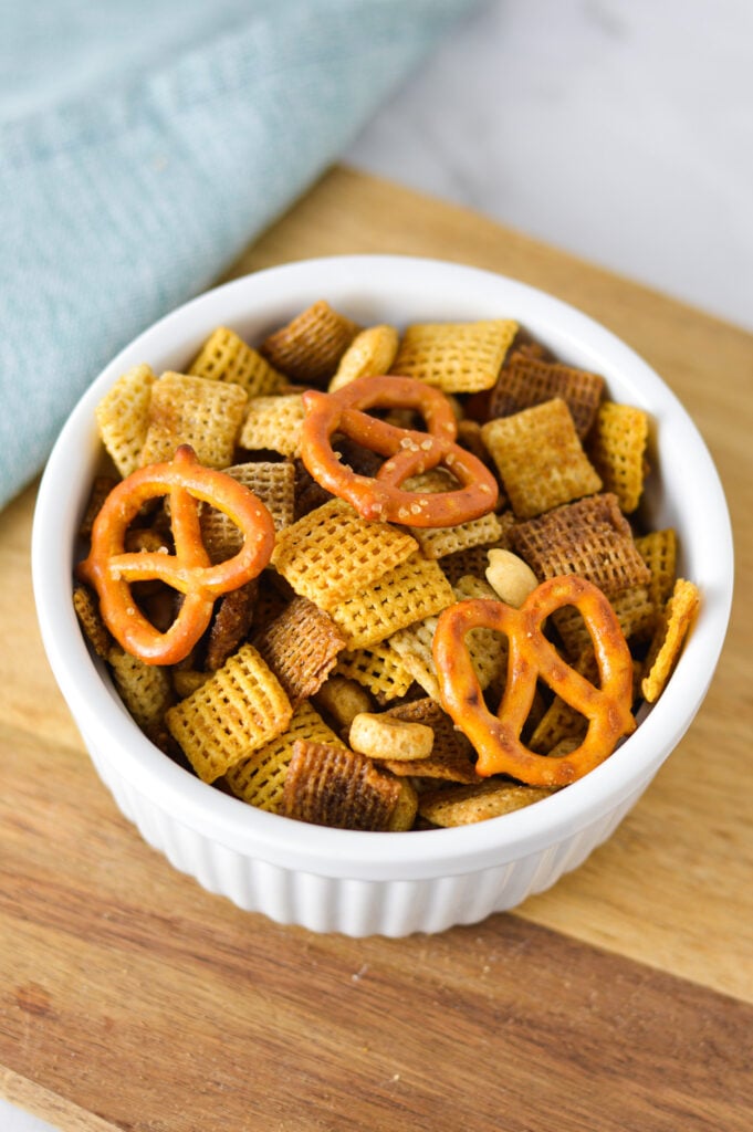 A small ramekin filled with Bold Chex Mix, with the crunchy pretzels, chex cereal and cheerios mixed into one delicious mix.