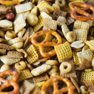A parchment paper lined baking sheet filled with freshly baked Bold Chex Mix, with the crunchy nut and Chex cereal mix golden brown.
