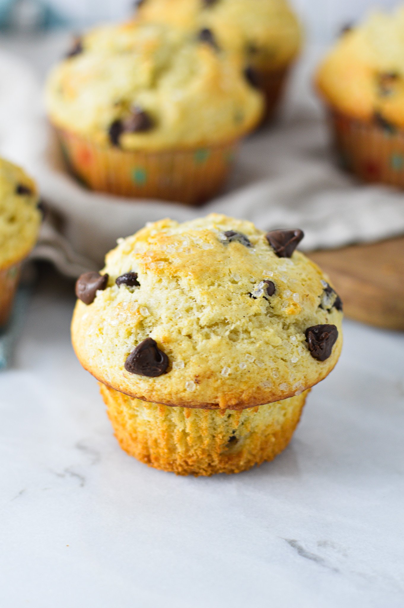 Easy Chocolate Chip Muffins, with semi-sweet chocolate chips and coarse sugar on top of the fluffy muffins.