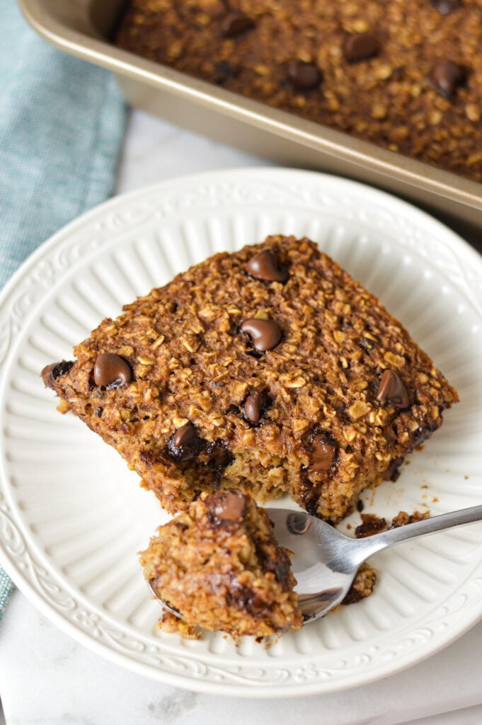 A small plate with some Double Chocolate Baked Oatmeal with a small spoon taking a piece of the hearty oatmeal.