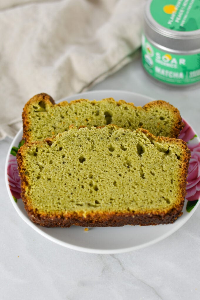 Freshly baked Matcha Pound Cake with a container of green tea powder in the background.
