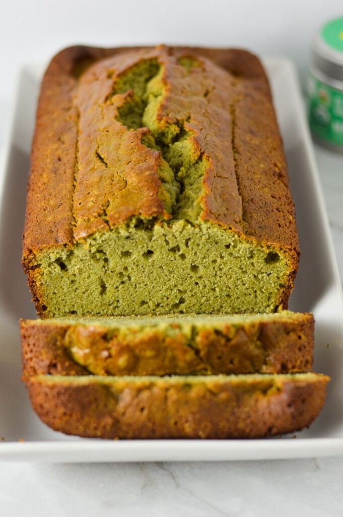 A golden brown loaf of Matcha Pound Cake freshly sliced, showing the vibrant green inside.