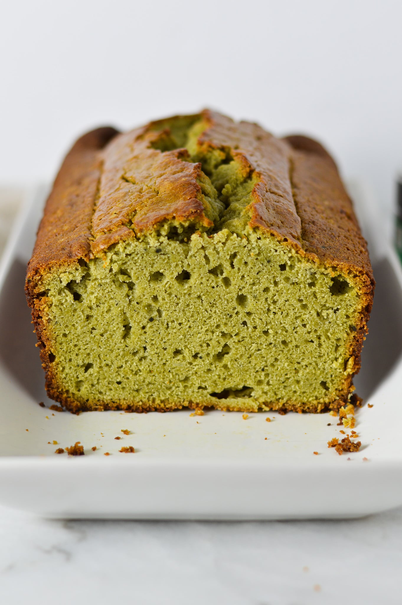A cut loaf of Matcha Pound Cake, with a golden top and a vibrant green color on the inside.