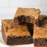 A plateful of Mayonnaise Brownies, with a bite taken out of one of the homemade brownies, showing its fudgy texture.