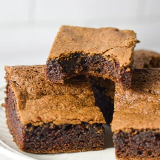 A plateful of Mayonnaise Brownies, with a bite taken out of one of the homemade brownies, showing its fudgy texture.