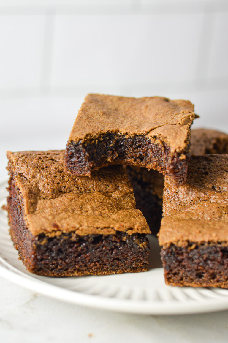 A plateful of Mayonnaise Brownies, with a bite taken out of one of the homemade brownies, showing its fudgy texture.