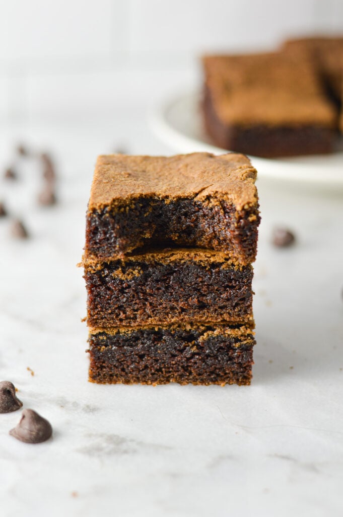 A stack of homemade Mayonnaise Brownies, with some semisweet chocolate chips in the background.
