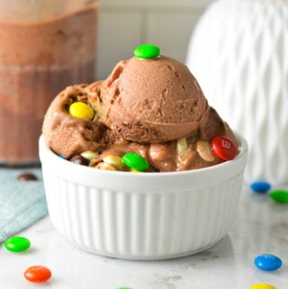 A small white bowl filled with Ninja Creami 3 Ingredient M&M Chocolate Ice Cream, with some chocolate M&Ms surrounding the Ninja Creami chocolate ice cream.