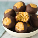 A small bowl full of Rice Krispie Buckeyes, with a bite taken out of one of them showing the crispy texture.