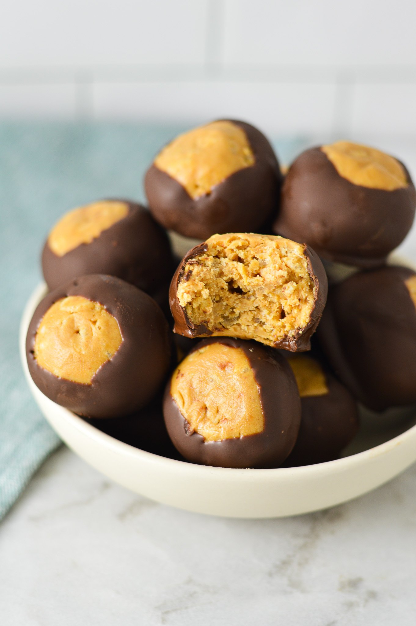 A small bowl full of Rice Krispie Buckeyes, with a bite taken out of one of them showing the crispy texture.
