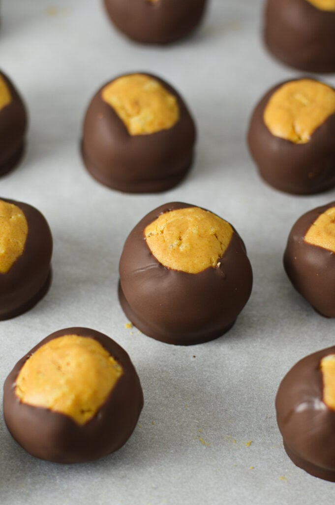 A wax paper lined cookie sheet with no bake Rice Krispie Buckeyes lined on top.