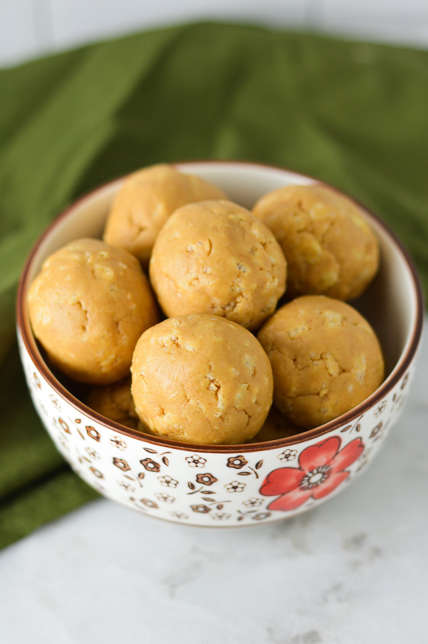 A small bowl with Rice Krispies Peanut Butter Balls, with the Rice Krispie cereal showing through the no bake peanut butter balls.