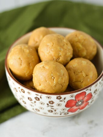 A small bowl filled with Rice Krispies Peanut Butter Balls, with the crispy rice cereal visible on the surface of the no bake peanut butter balls.