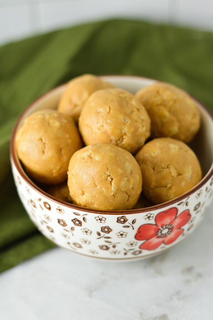 A small bowl filled with Rice Krispies Peanut Butter Balls, with the crispy rice cereal visible on the surface of the no bake peanut butter balls.