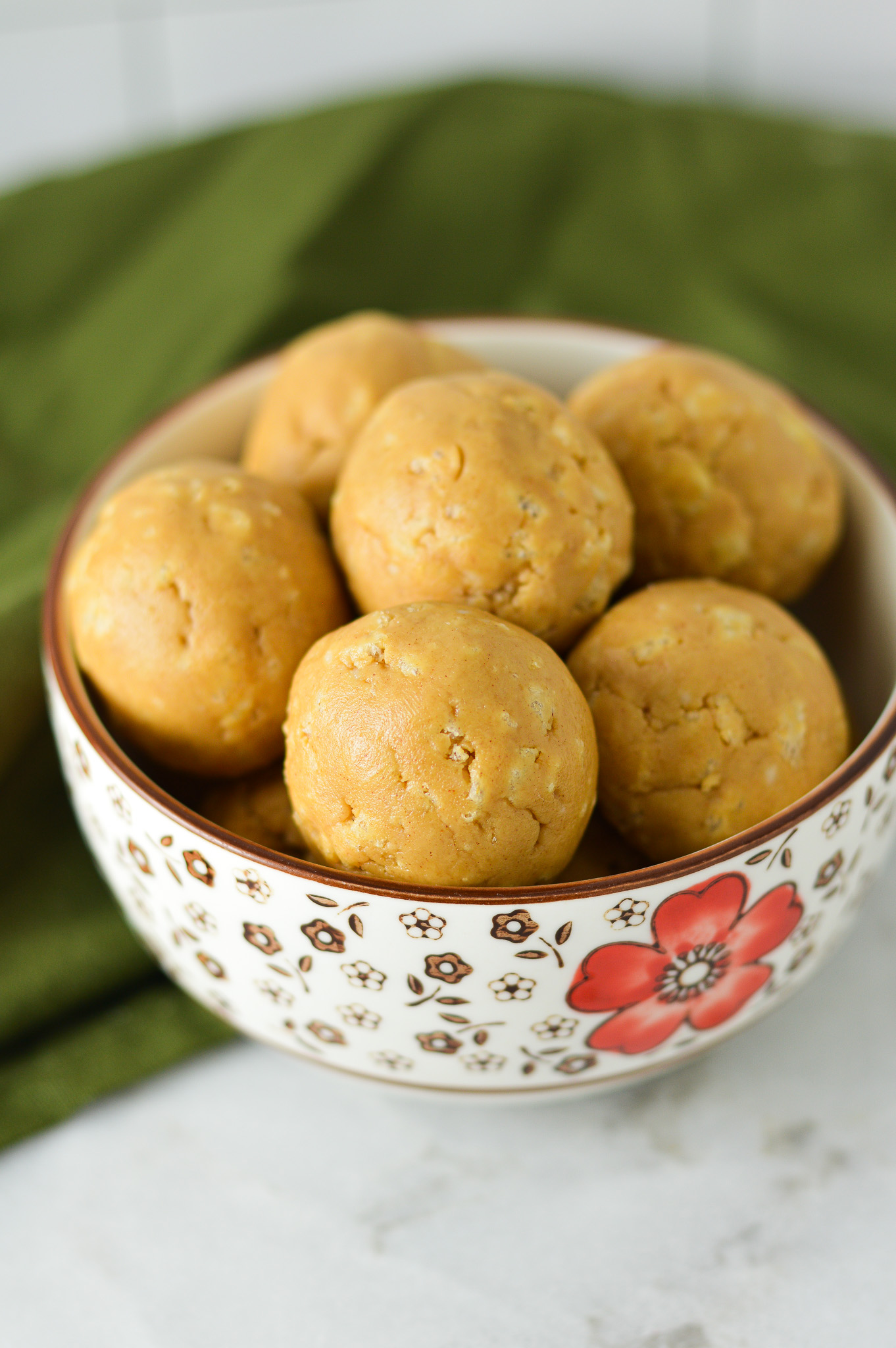 A small bowl filled with Rice Krispies Peanut Butter Balls, with the crispy rice cereal visible on the surface of the no bake peanut butter balls.