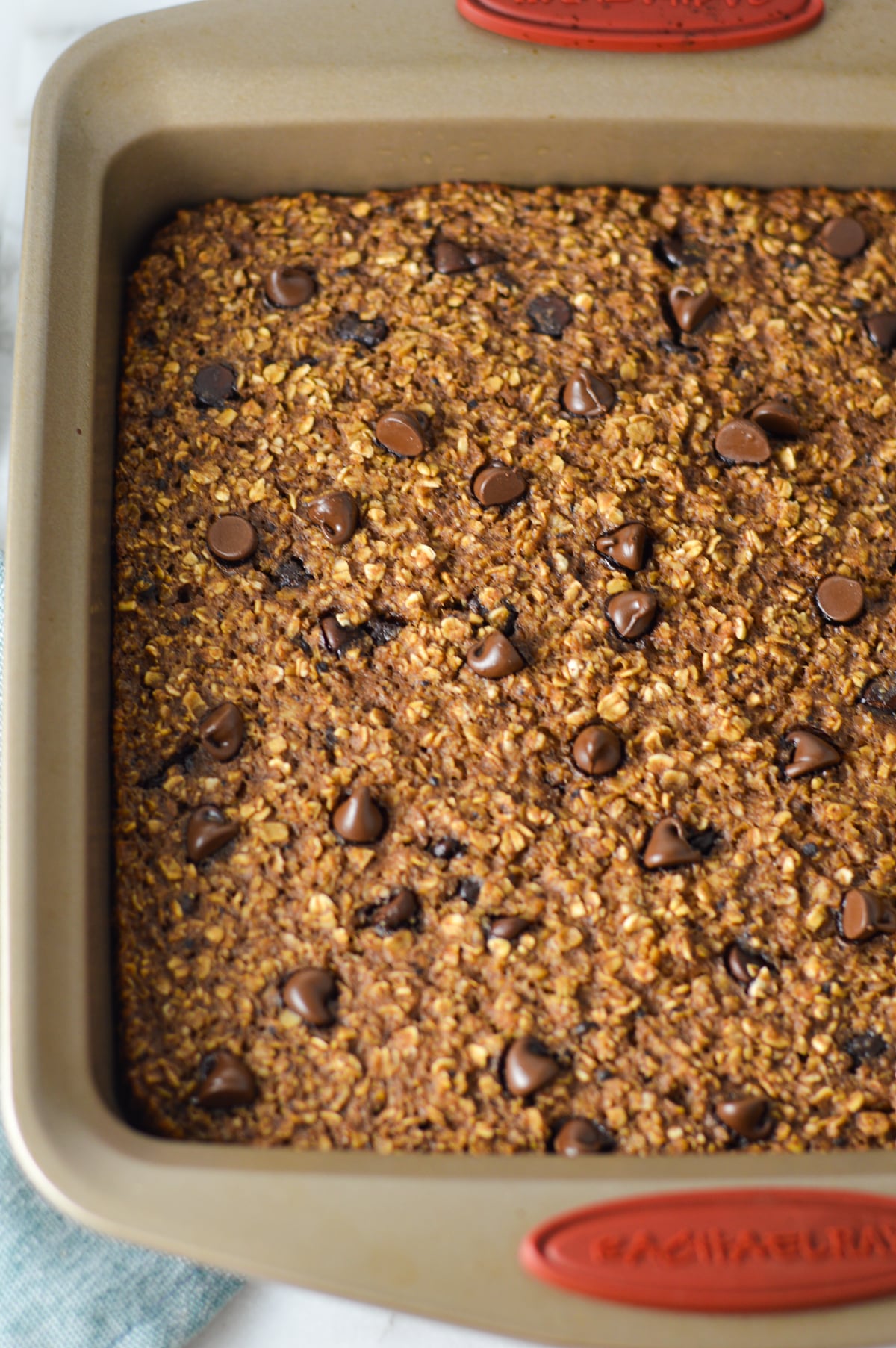 Freshly baked Double Chocolate Baked Oatmeal in a square pan, with semi-sweet chocolate chips sprinkled on top.