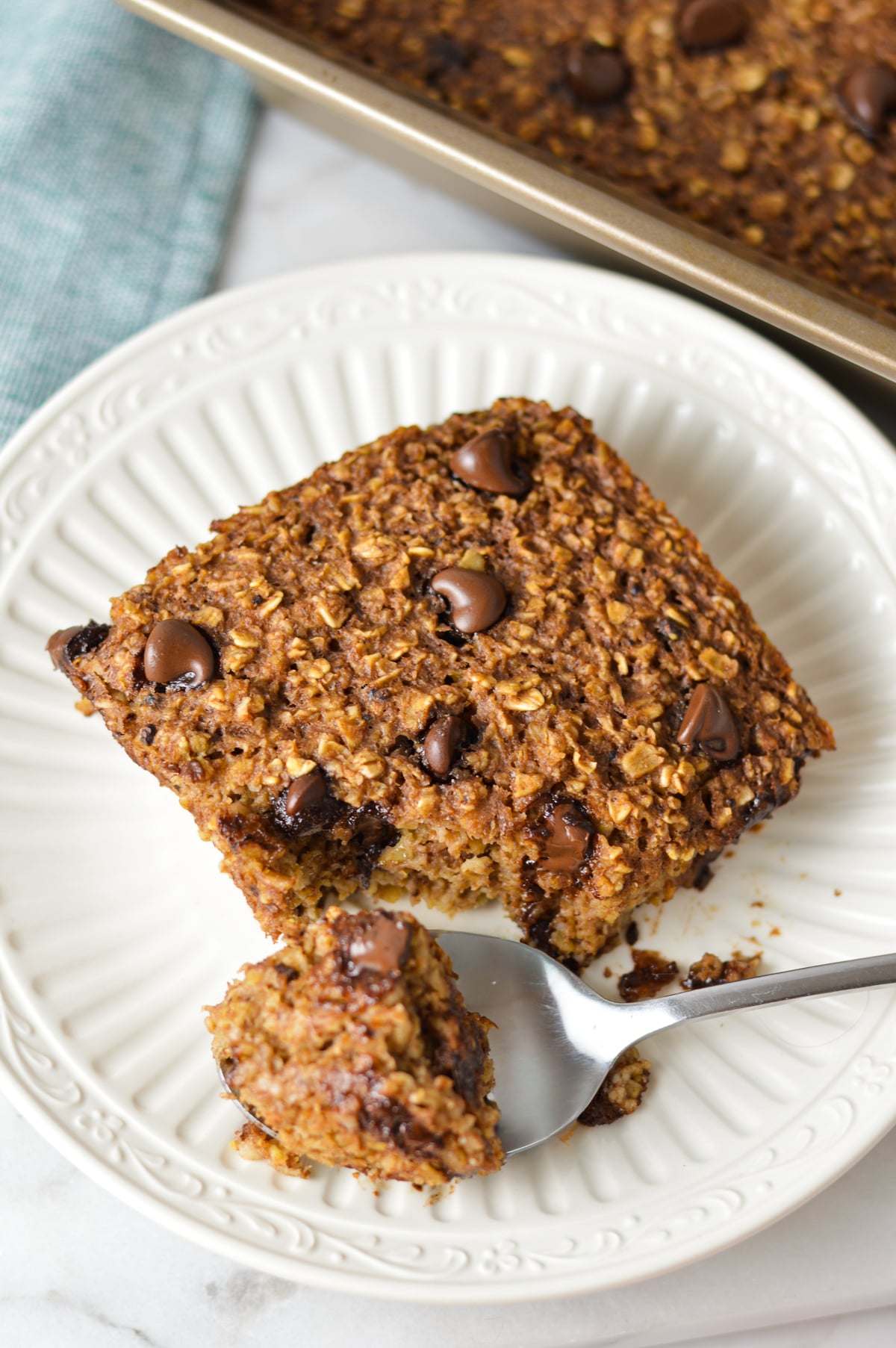 A small plate with some Double Chocolate Baked Oatmeal with a small spoon taking a piece of the hearty oatmeal.