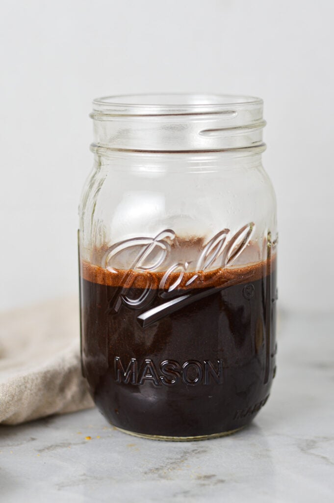 A mason jar half filled with Homemade Chocolate Sauce.