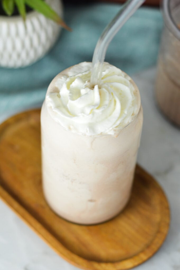Whipped cream topped Ninja Creami Frozen Hot Chocolate, with a clear straw sticking out of the frozen treat.