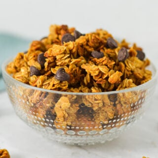 A small mixing bowl filled with Peanut Butter Chocolate Chip Granola, with the peanut butter granola clusters golden brown against the extra chocolate chips on top.