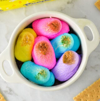 An oven safe container filled with festive Peeps S'mores Dip, with the colorful marshmallow chicks slightly golden brown from the oven.