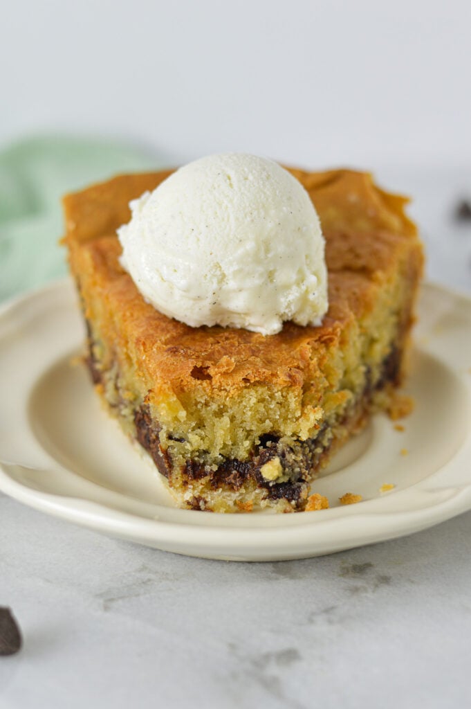 A slice of Chocolate Chip Cookie Pie topped with vanilla bean ice cream, with a bite taken out showing its chocolatey center.