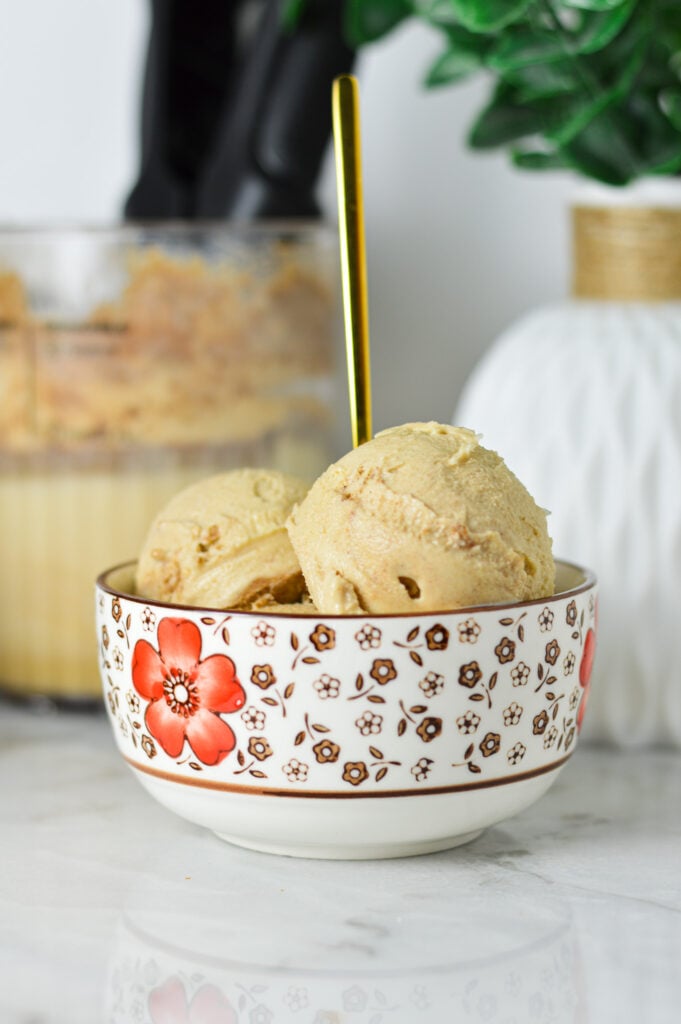 A small bowl of Ninja Creami Cinnamon Protein Ice Cream with a gold spoon sticking out of the creamy ice cream.