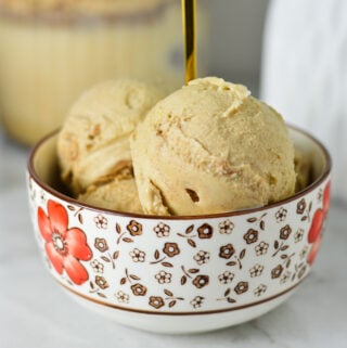 A small bowl of Ninja Creami Cinnamon Protein Ice Cream, with a Ninja Creami container in the background with some extra ice cream.