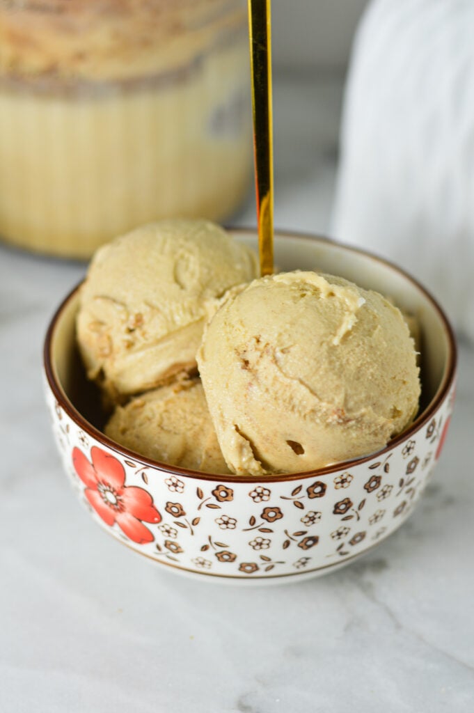 Scoops of Ninja Creami Cinnamon Protein Ice Cream in a small bowl, with a small spoon sticking out of the homemade ice cream.