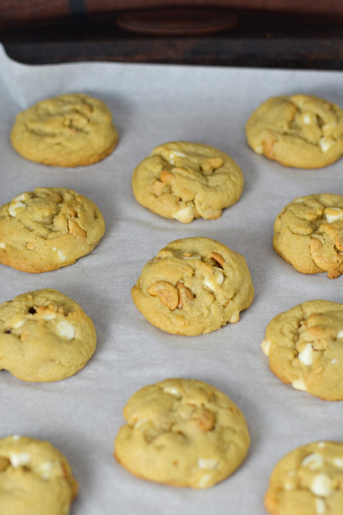 Freshly baked White Chocolate Cashew Cookies on a parchment paper lined baking sheet.