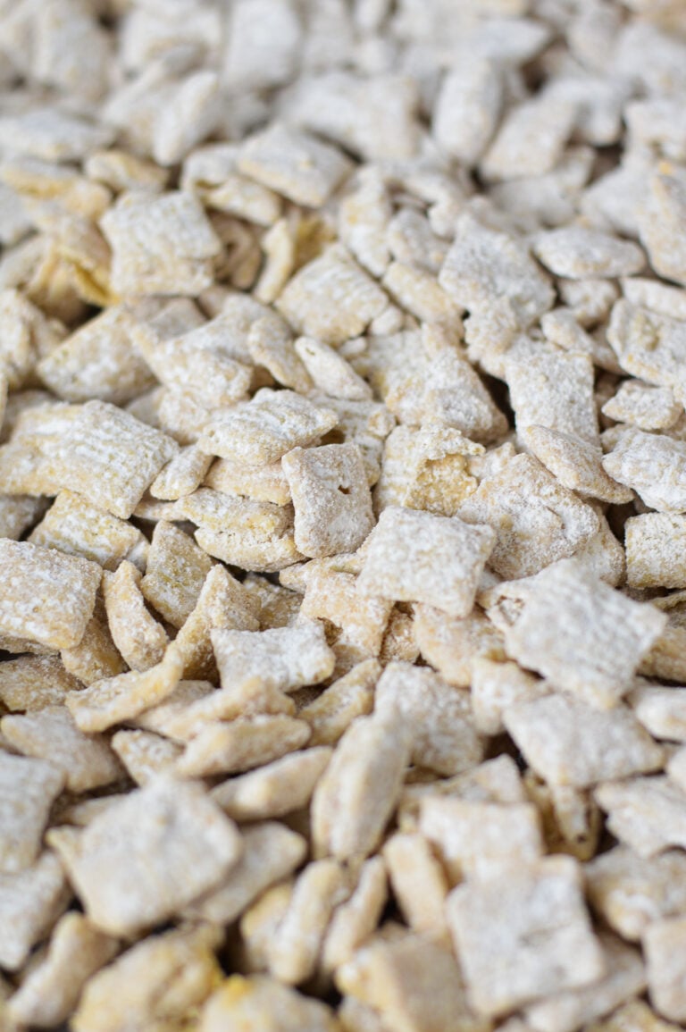 A parchment paper lined baking sheet filled with White Chocolate Puppy Chow.