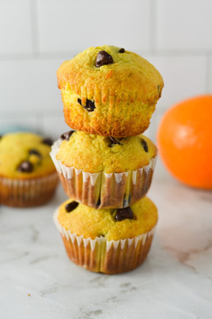 A stack of Orange Chocolate Chip Muffins, with the paper liner taken off the top muffin.