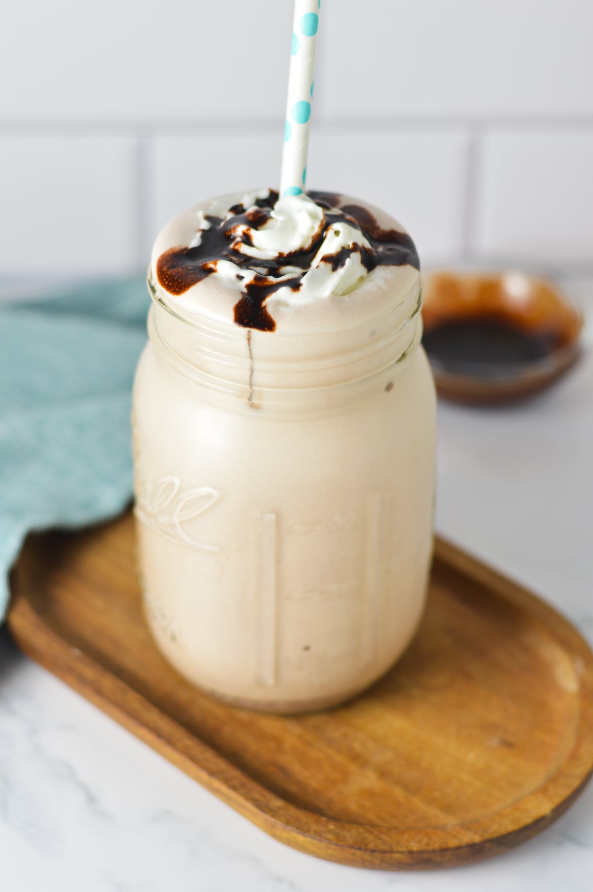 A 2-ingredient chocolate milkshake made in a Ninja Slushi, topped with whipped cream and chocolate sauce drizzle in a glass mason jar.