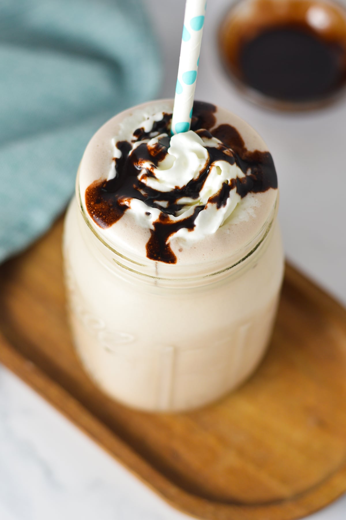 Close-up of a chocolate milkshake in a mason jar topped with whipped cream and a chocolate sauce drizzle.