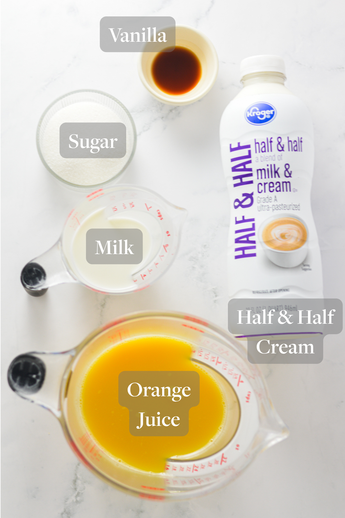 All the ingredients needed to make a Ninja Slushi Orange Julius laid out on a marble surface.
