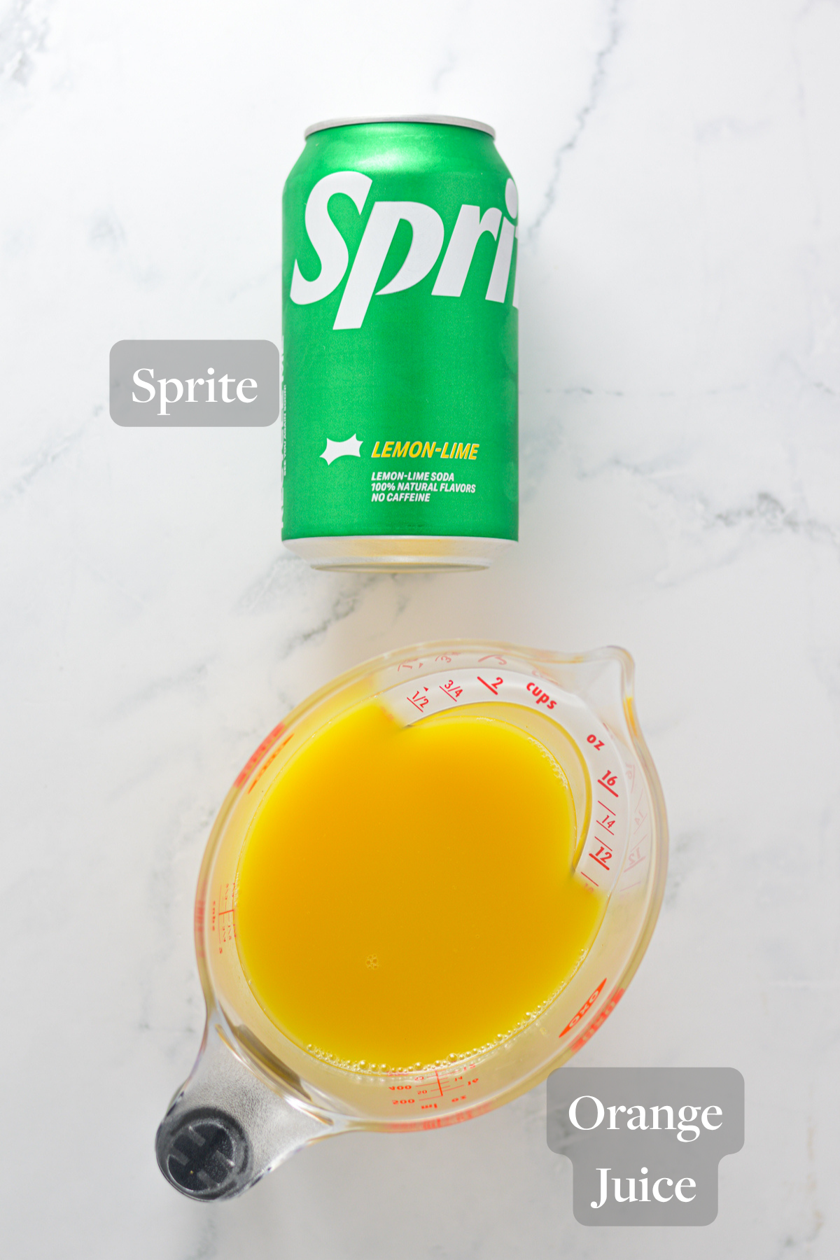 All of the ingredients needed to make a Ninja Slushi Virgin Mimosa, laying on a marble surface.