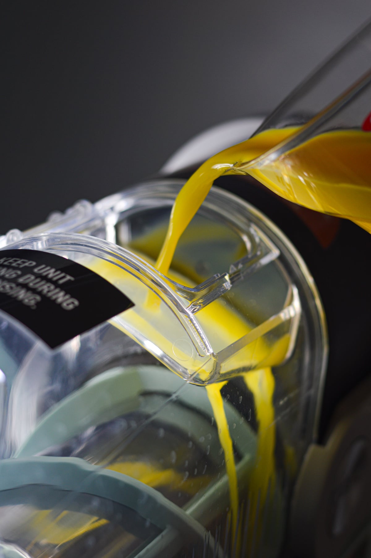 Orange juice being poured into the vessel of a Ninja Slushi machine.