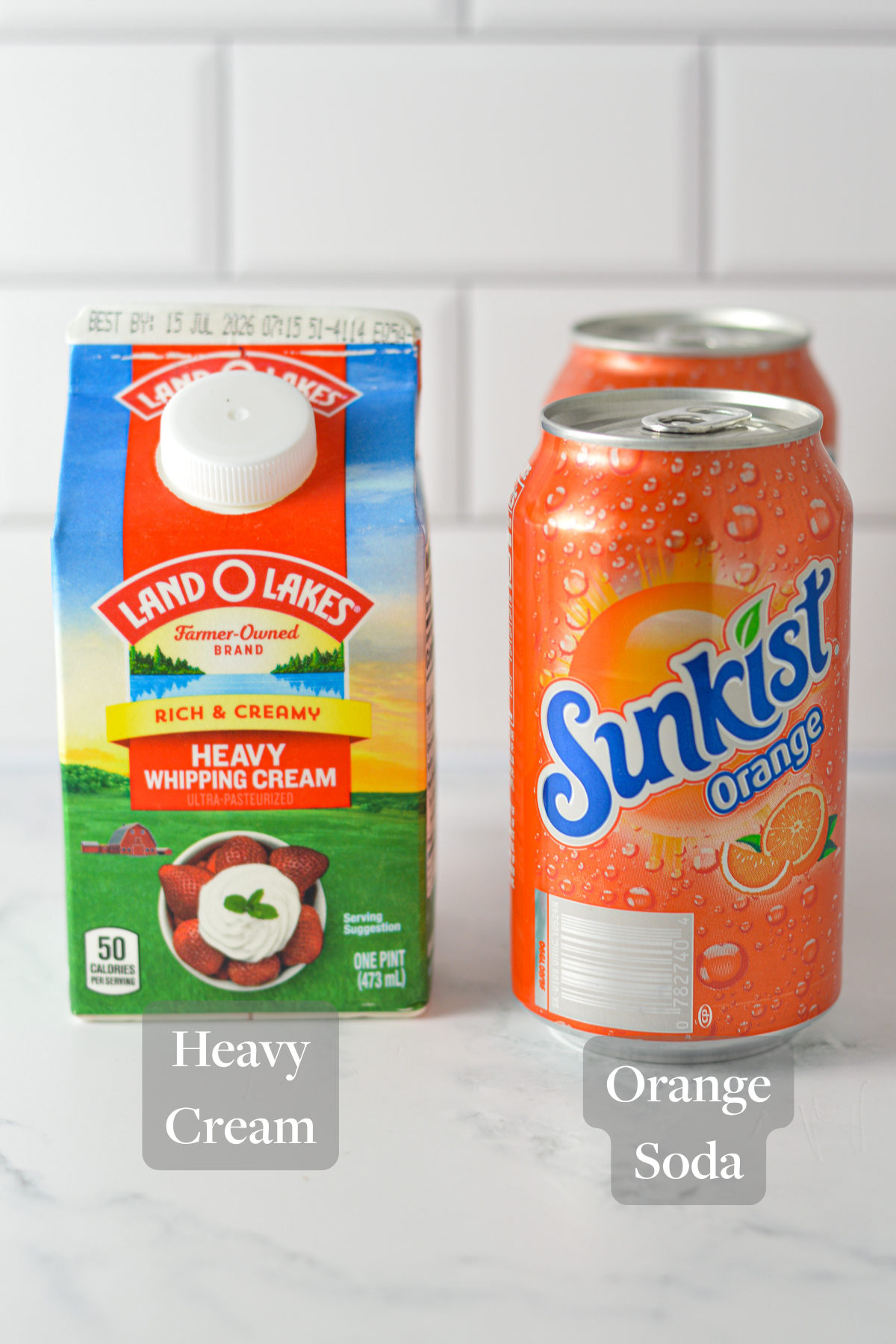 Heavy whipping cream and Sunkist orange soda on a marble kitchen counter.