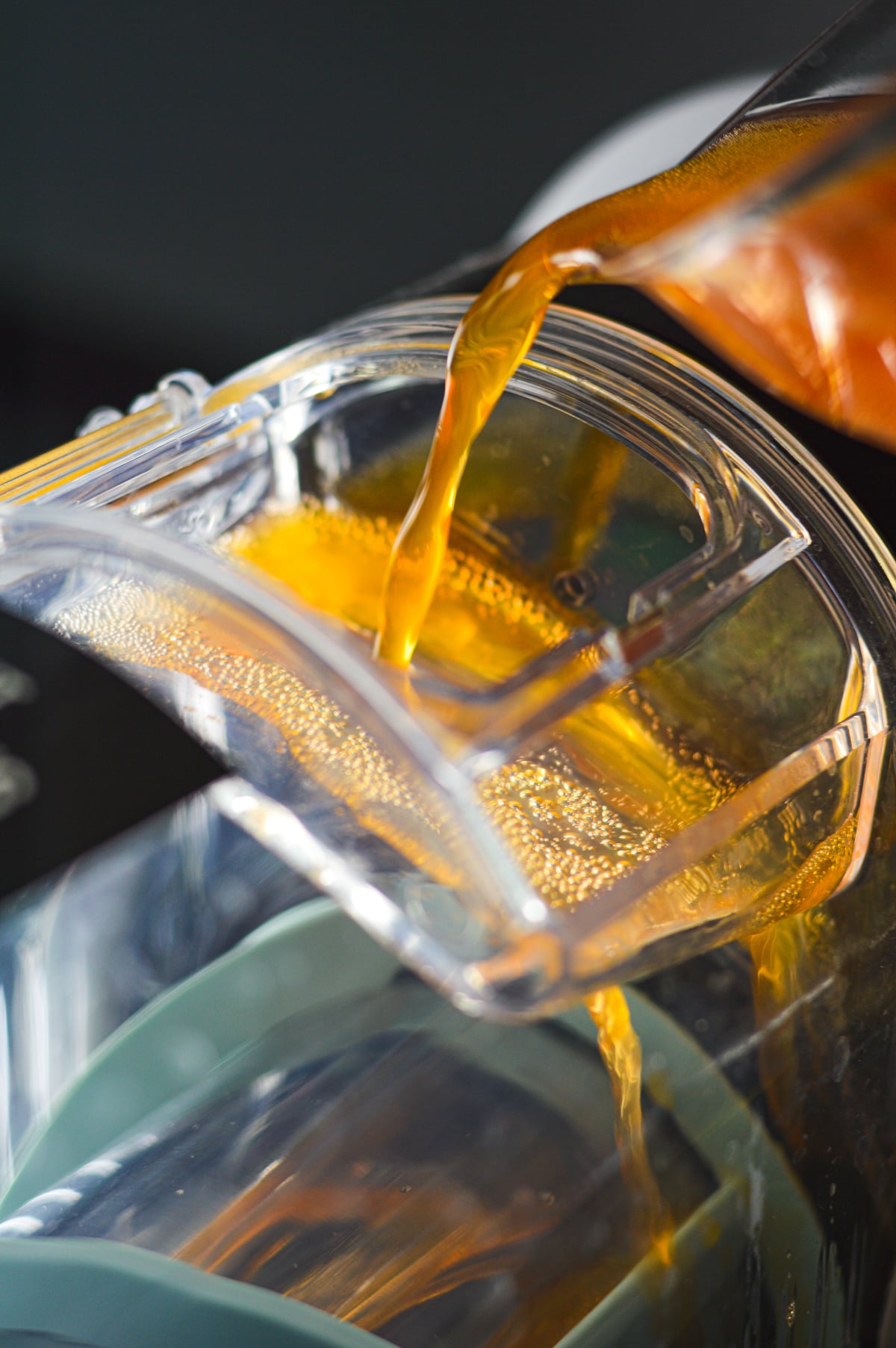 A can of orange soda being poured into the vessel of a Ninja Slushi machine.