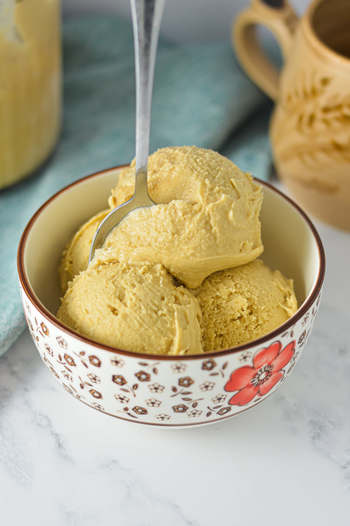 Scoops of creamy coffee ice cream in a bowl with a spoon resting inside, set against a warm, rustic background.
