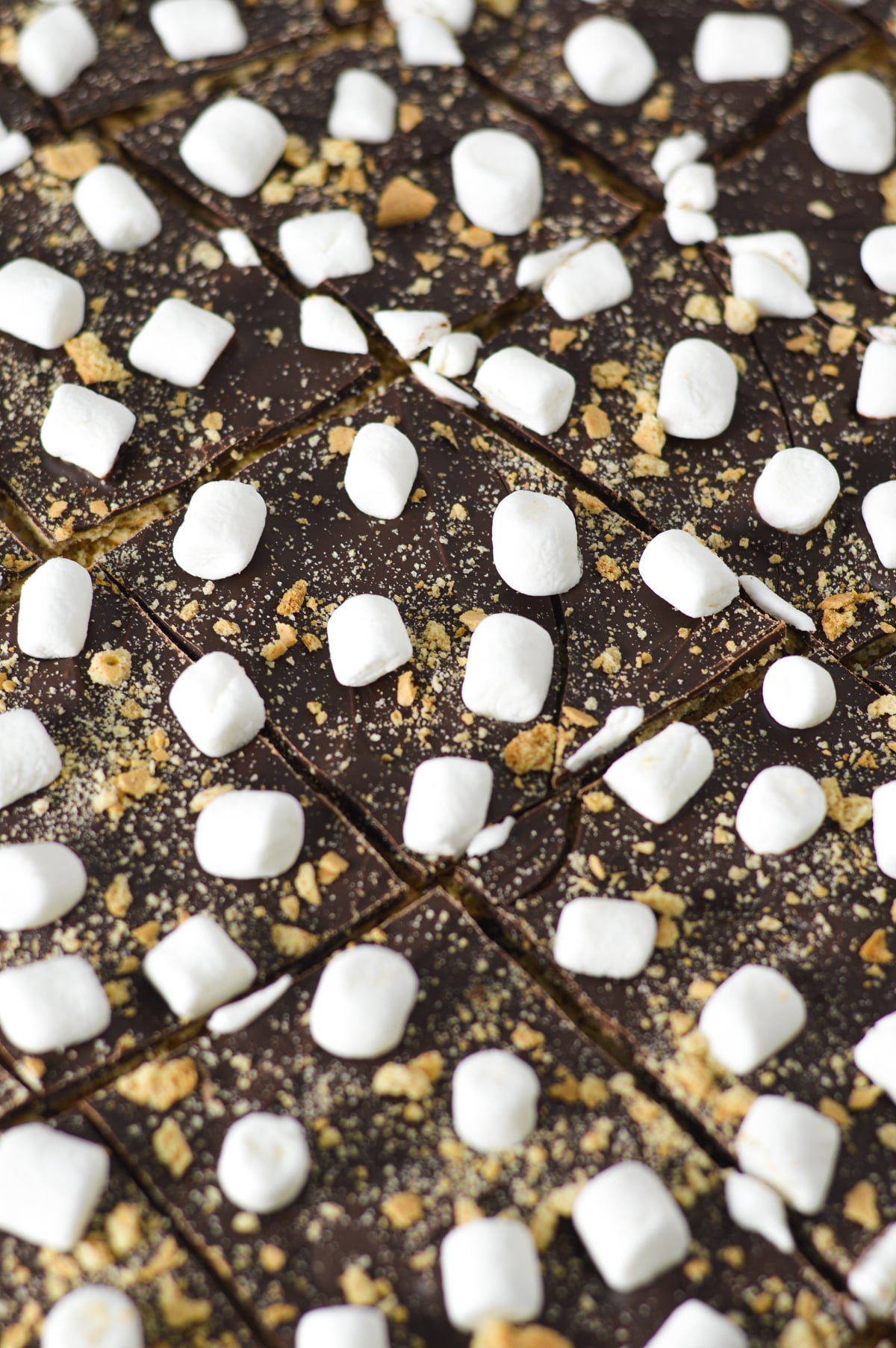 A close-up view of S'mores Chocolate Bark topped with mini marshmallows and sprinkled with graham cracker crumbs.