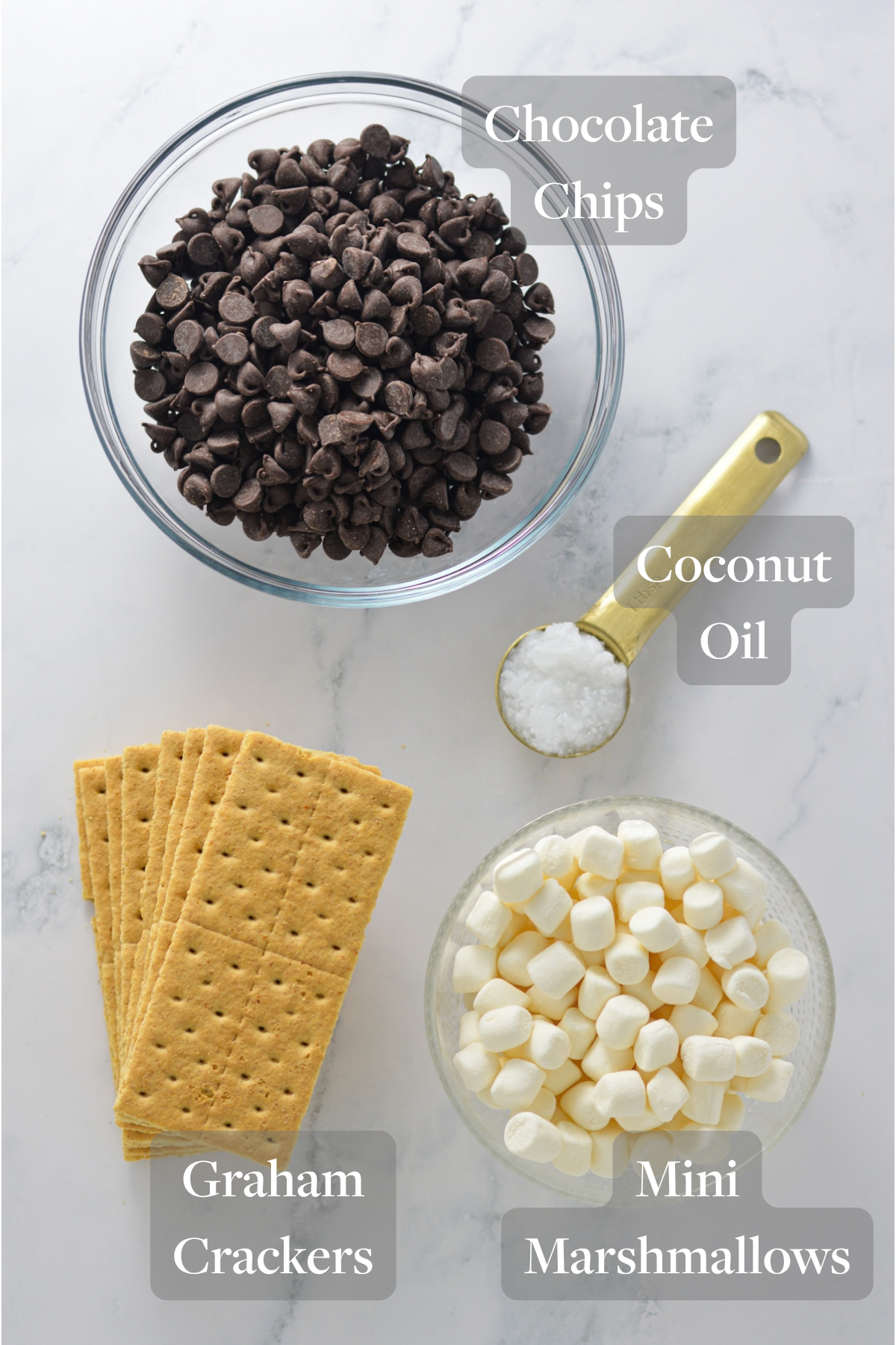 All the ingredients you need to make S'mores Chocolate Bark laid out on a marble surface.
