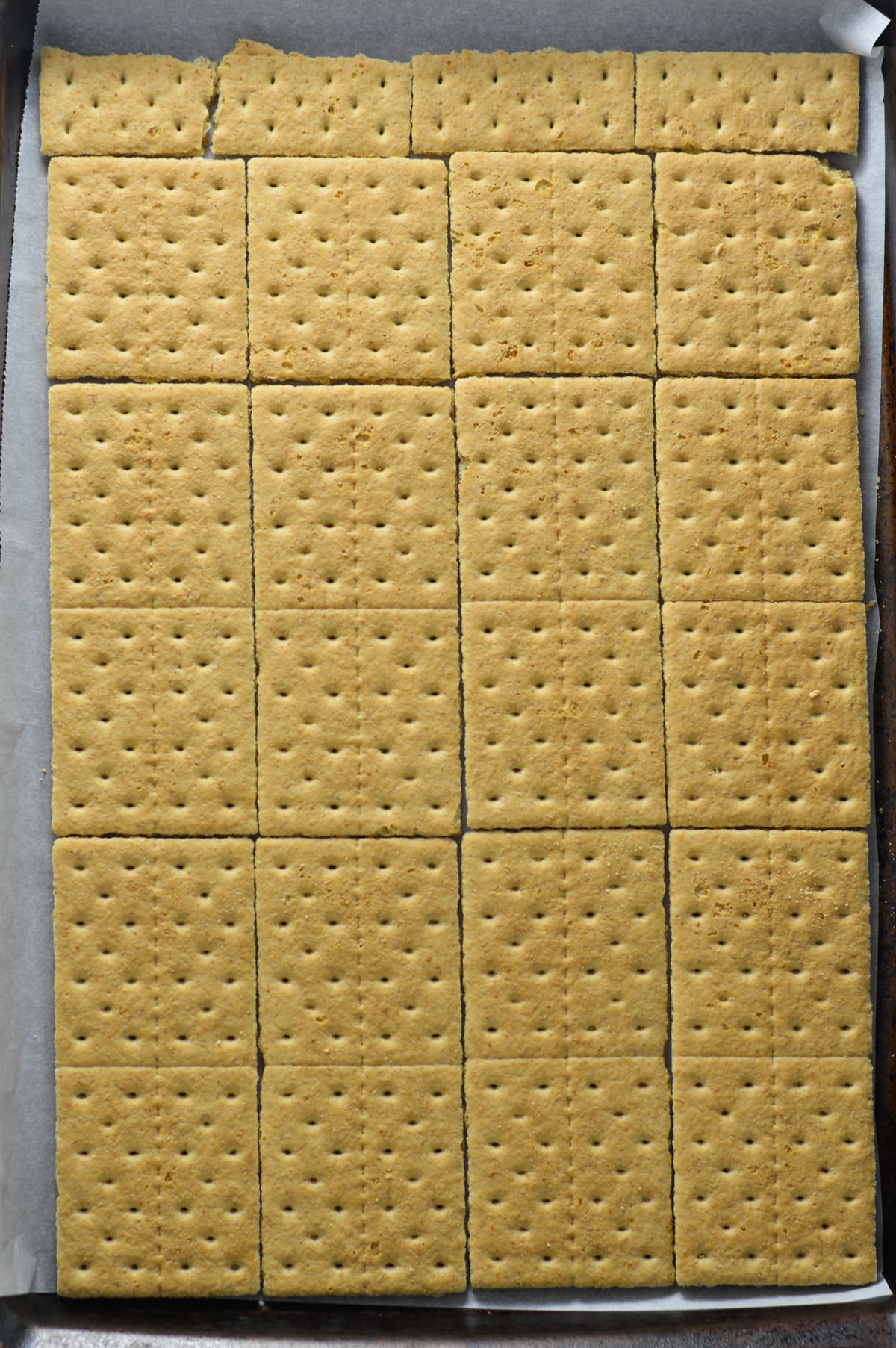 Whole graham crackers laid out in a single layer on a parchment paper lined baking sheet.